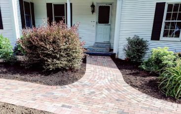 A brick walkway in front of a house.