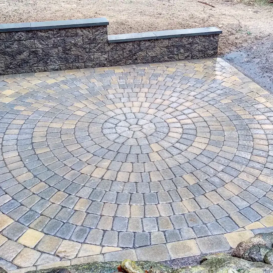680270192a70c_IMG_20211214_082518_047 (1) A circular pattern of brick paving with stone wall.