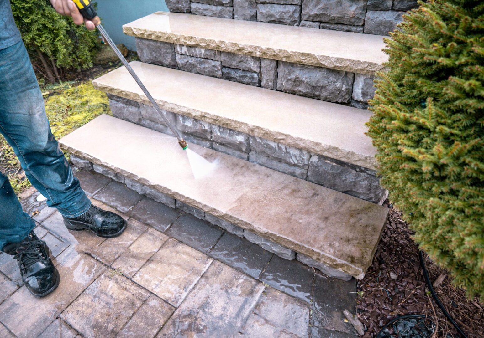Pressure washing stone steps for cleaning.