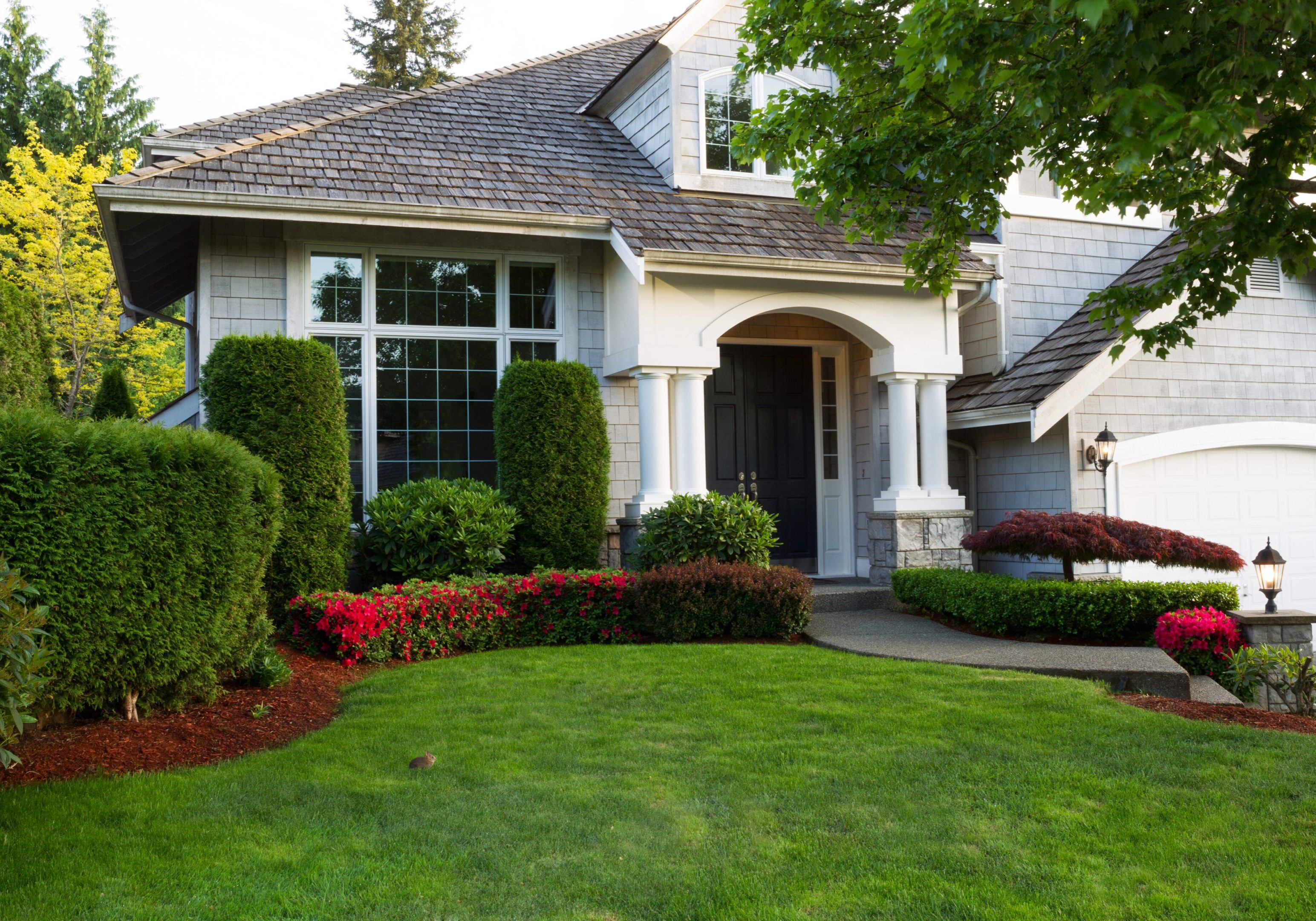 House with manicured lawn and shrubs.
