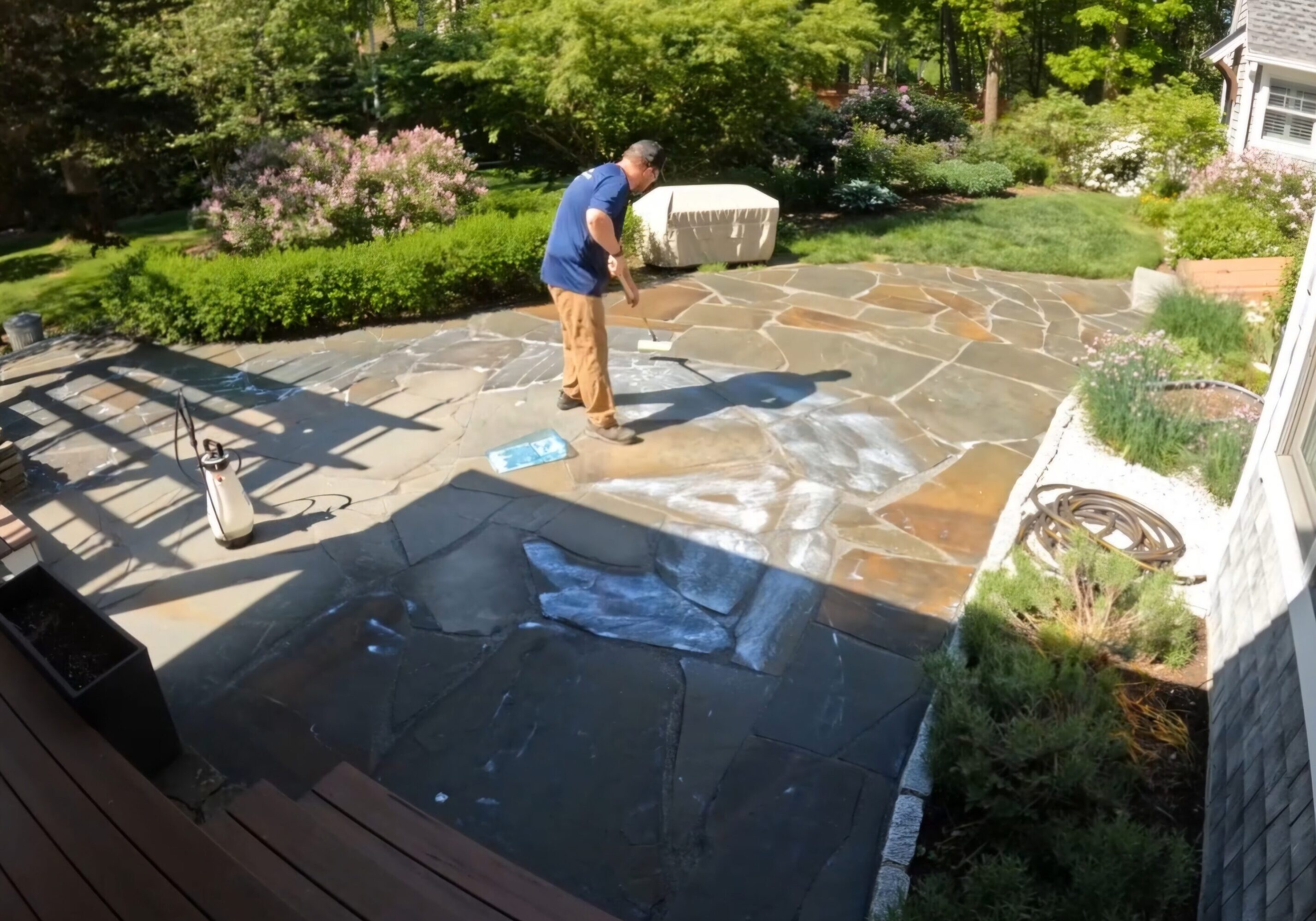 A man is painting the patio with white paint.